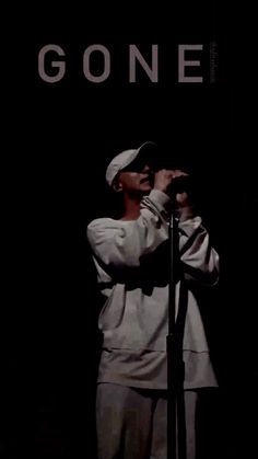 a woman singing into a microphone in front of a black background with the words gone on it