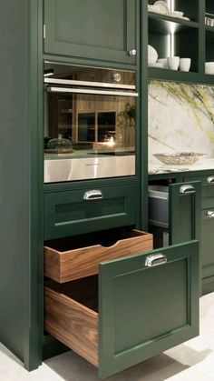 a kitchen with green cupboards and drawers in it's center, including an oven