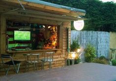 an outside bar with tables and chairs in front of it, next to a fence