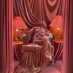 an image of a person sitting in a chair that is covered by curtains and has the caption's name on it