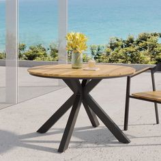 a wooden table with two chairs next to it and the ocean in the back ground