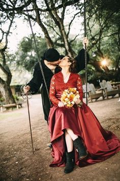 a man and woman are kissing on a swing in the park while dressed up as witches