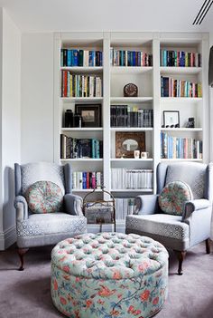 a living room filled with lots of furniture and bookshelves covered in bookcases