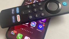 two remote controls sitting next to each other on top of a white table with various app icons