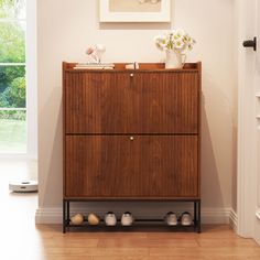 a wooden cabinet sitting in the corner of a room next to a door with shoes on it