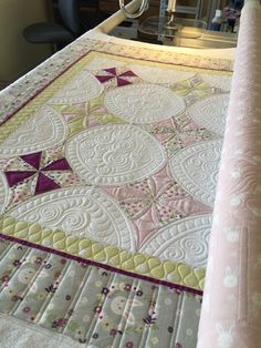 a quilted table runner on top of a bed next to a desk and chair