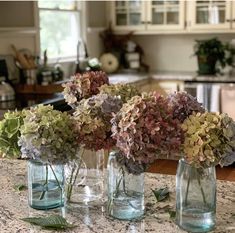 three vases filled with flowers sitting on top of a counter