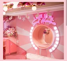 a pink room with flowers and lights on the ceiling, in front of a circular mirror