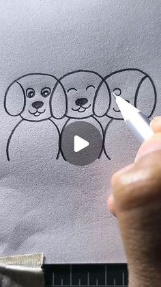 someone is drawing three dogs on a t - shirt with a white marker and pen