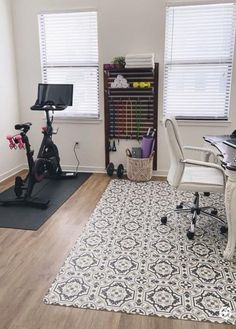 a home office with an exercise bike and desk