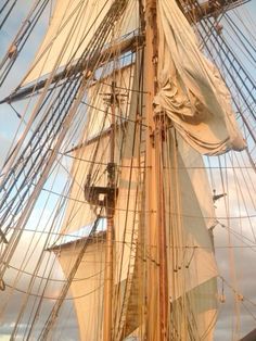 an old sailing ship with white sails on the water