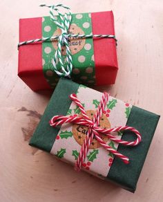 two wrapped presents sitting next to each other on top of a wooden table with red and green ribbons