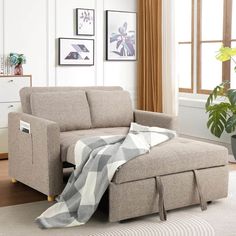 a living room scene with focus on the couch and ottoman that has a blanket draped over it