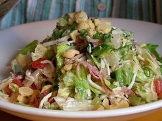 a salad in a white bowl on top of a wooden table with a striped cloth