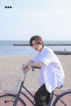 a man riding a bike on the beach with a basket in front of his back