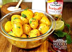 a glass bowl filled with yellow potatoes on top of a wooden cutting board next to a jar of mustard