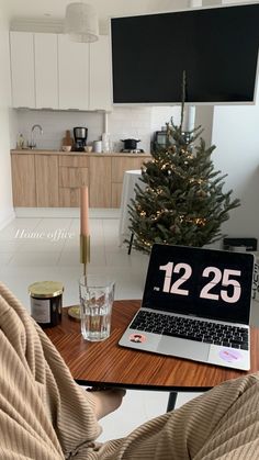 a laptop computer sitting on top of a wooden table in front of a christmas tree