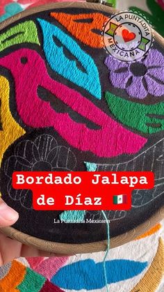 someone is holding up a colorful piece of art with the words bordado jalapa de diaz on it