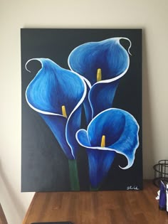 a painting of blue flowers on a black background in a room with wood flooring