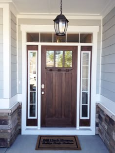 a front door with a welcome mat and light fixture hanging from it's side