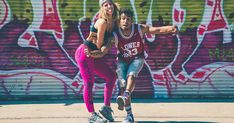 two people on skateboards in front of a wall with graffiti and spray painted walls