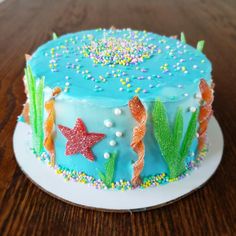 a blue cake decorated with stars, seaweed and sprinkles on a plate