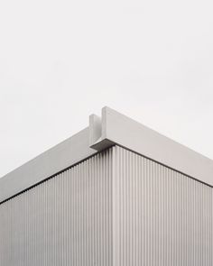 an airplane is flying over the top of a large building with metal sidings on it's sides