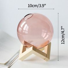 a pink glass ball sitting on top of a wooden stand