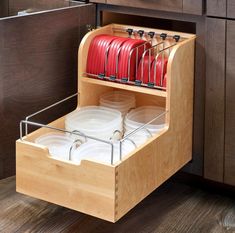 an open drawer with plates and glasses in it on the side of a kitchen counter