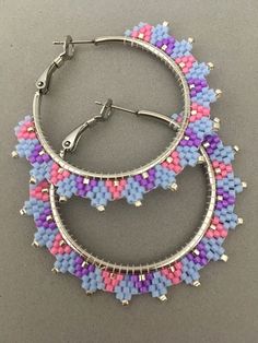 two pairs of hoop earrings with multicolored seed beading on the ends and silver findings