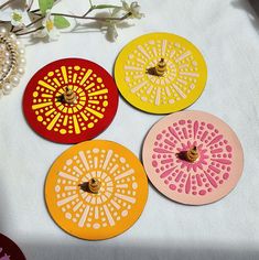 four coasters with designs on them are sitting on a table next to a bead necklace