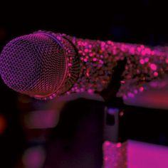 a microphone that is sitting in front of a purple and black background with some lights on it