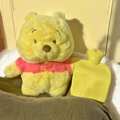 a yellow teddy bear sitting on top of a bed next to a bottle of perfume