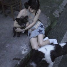 a woman sitting on the ground next to a black and white cat