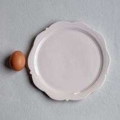 an egg sitting on top of a white plate next to it's own shell