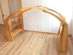 a wooden arch sitting on top of a hard wood floor next to a book shelf