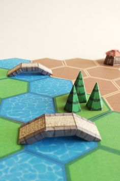 a board game with trees and buildings on the boards next to water, sand and grass