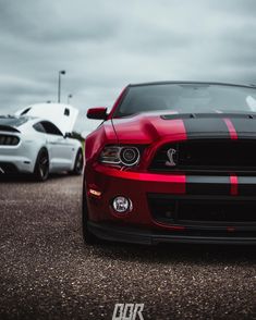 two cars parked next to each other in a parking lot with cloudy skies behind them