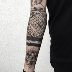 a man's arm with a flower of life tattoo on it and an eye