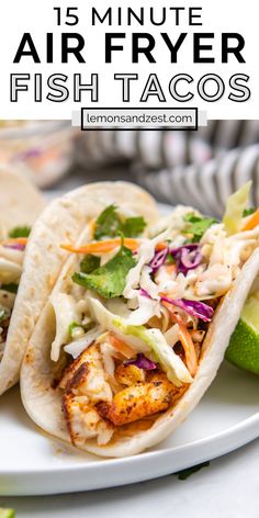 three fish tacos on a white plate with lime wedges and cilantro