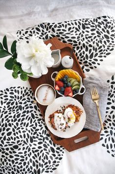 a wooden tray topped with plates and bowls filled with food next to a white flower