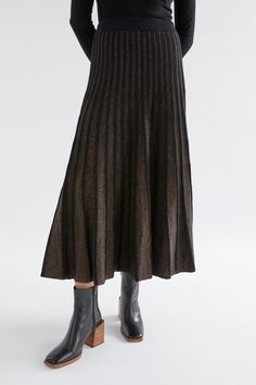 Product Details Glitter and flow. The Glittra Metallic Skirt is a long A-line knit skirt with an elasticised waistband that is designed to hit around the ankle bone. This heavier weight skirt features an all over shimmer effect from the metallic thread plaited through the yarn, and the knit design also has a contrasting non-shimmer waistband and vertical lines down the skirt. Long knit skirt A-line shape Elasticised waistband for added comfort All over shimmer effect Contrasting black waistband and vertical lines Soft feel on skin This design is part of the conscious edit Material 82% Organic Cotton 11% Polyester 6% Metallic 1% Elastane This ribbed knit incorporates a sparkly yarn throughout to offer a metallic finish. Certified organic cotton is grown without the use of synthetic fertiliz Long Knit Skirt, Black Knit Skirt, Lurex Knit, Edit Material, Handmade Knitwear, Aesthetic Feed, Metallic Sweater, Metallic Skirt, Vertical Lines