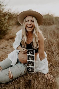 a woman sitting on the ground wearing jeans and a cowboy hat holding an old camera