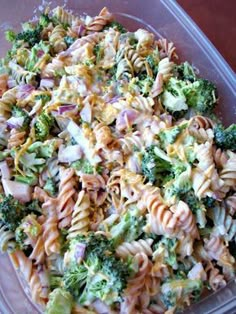 a pasta salad with broccoli and onions in a plastic container on a table