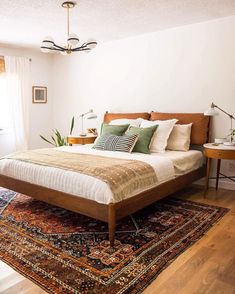 a large bed sitting on top of a wooden floor next to a window in a bedroom