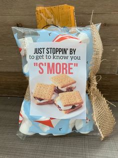 a bag of s'mores sitting on top of a wooden table next to a sign that says just stoppin'by to get to know you