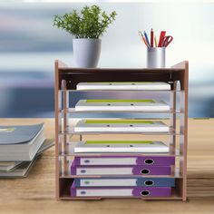 a stack of folders sitting on top of a wooden table next to a potted plant