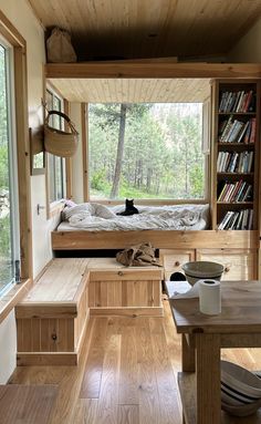 the interior of a tiny cabin with wood flooring and built in bookshelves