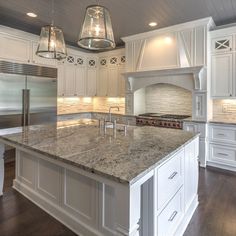 a large kitchen with white cabinets and granite counter tops, along with stainless steel appliances