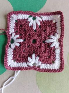 a crocheted square with white flowers on it sitting on top of a table